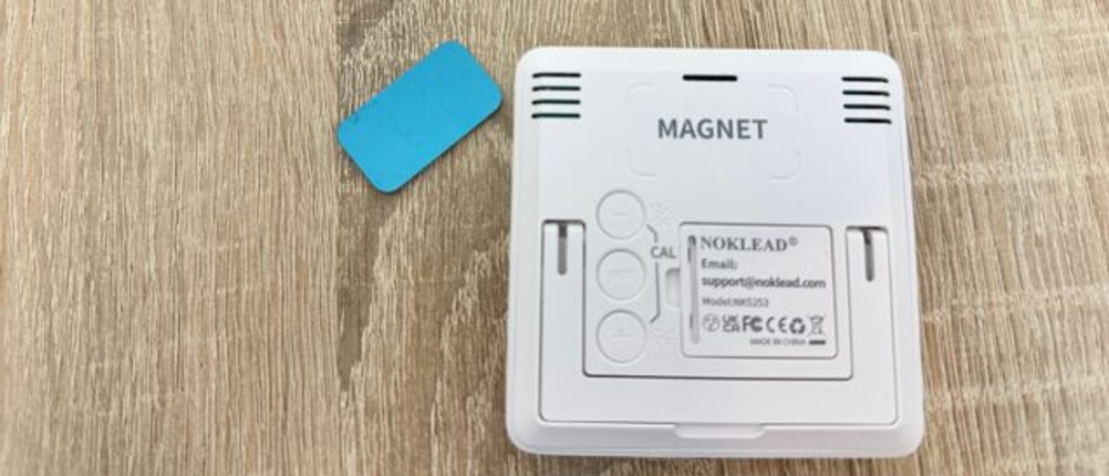 Ein Magnet zur Befestigung liegt neben einem Thermometer auf einem Tisch.