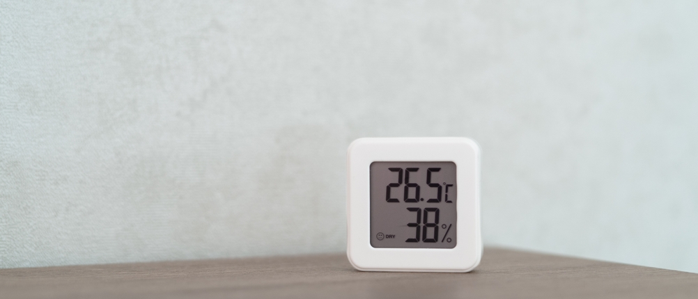 Ein kompaktes digitales Thermometer mit Hygrometer zeigt 26,5 Grad Celsius und 38 Prozent Luftfeuchtigkeit auf einem Tisch an.