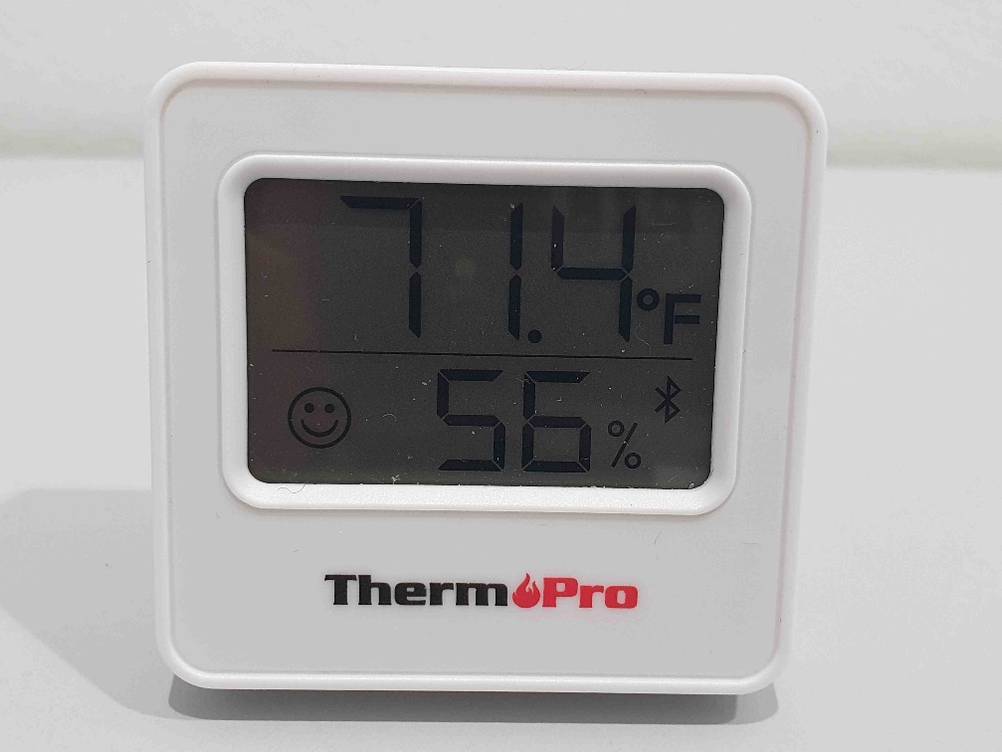 Ein getestetes Thermometer von vorne mit Display und Anzeige auf einer hellen Fläche.