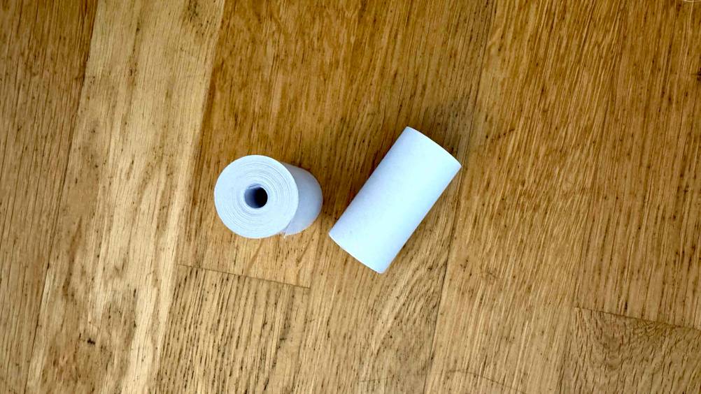 Thermopapier-Test: Zwei Rollen auf einer Holzfläche von oben, eine liegend, eine stehend.