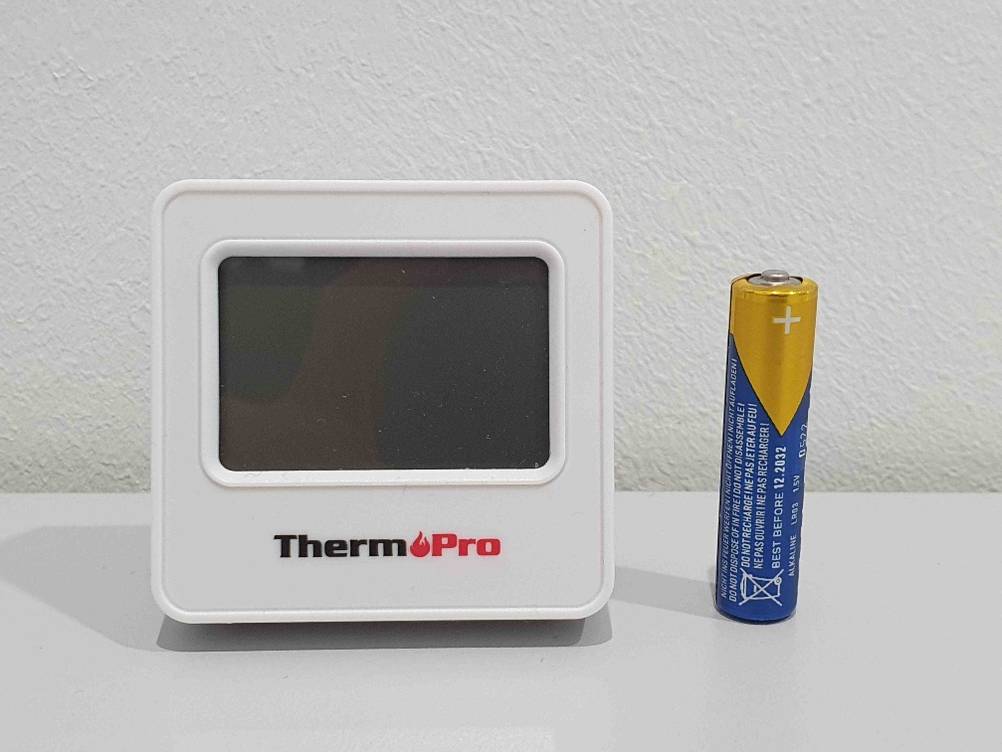Neben einem getesteten Smart-Home-Thermostat steht eine Batterie.