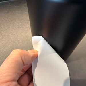 Eine Hand zieht einen Aufkleber von der Thermos Edelstahl Stainless King