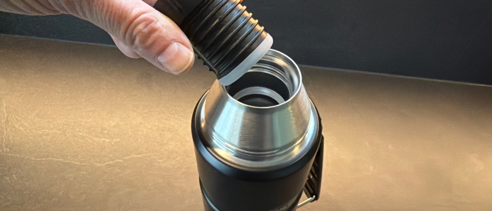 Eine Hand hält den Deckel der Thermos Edelstahl Stainless King fest