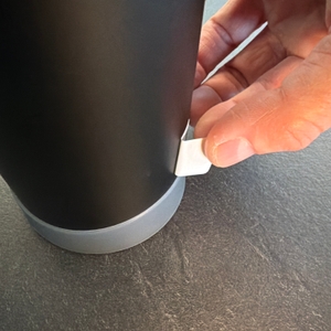 Eine Hand zieht einen Aufkleber von der Thermos Mountain