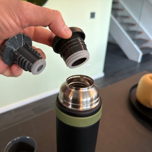 Eine Hand nimmt den Schraubverschluss aus der Thermos Mountain