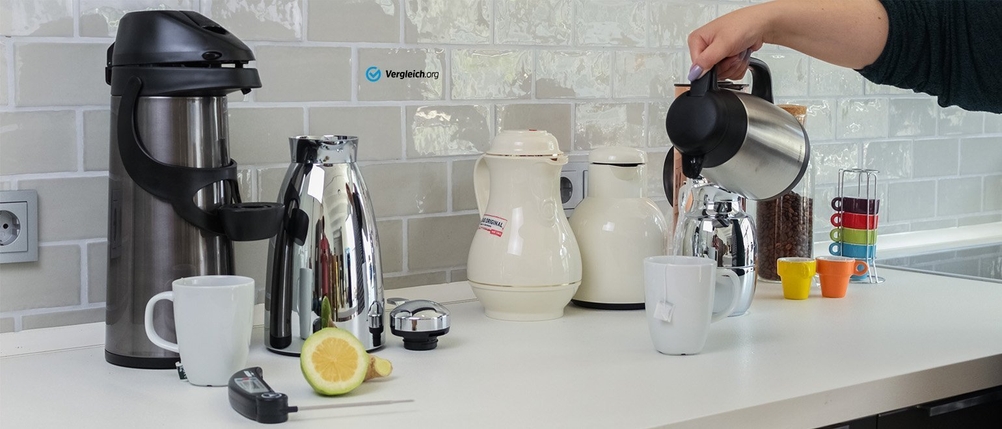 Zahlreiche Thermokannen stehen in einer Küche, aus einer wird in eine Tasse eingeschenkt.