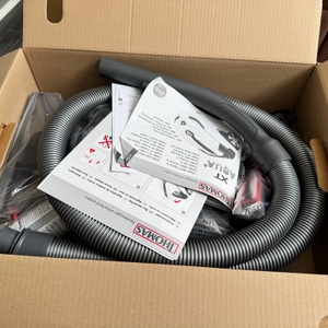 Im geöffneten Karton des Thomas Pet and Family Aqua+ sind ein Schlauch und die Anleitung zu sehen.