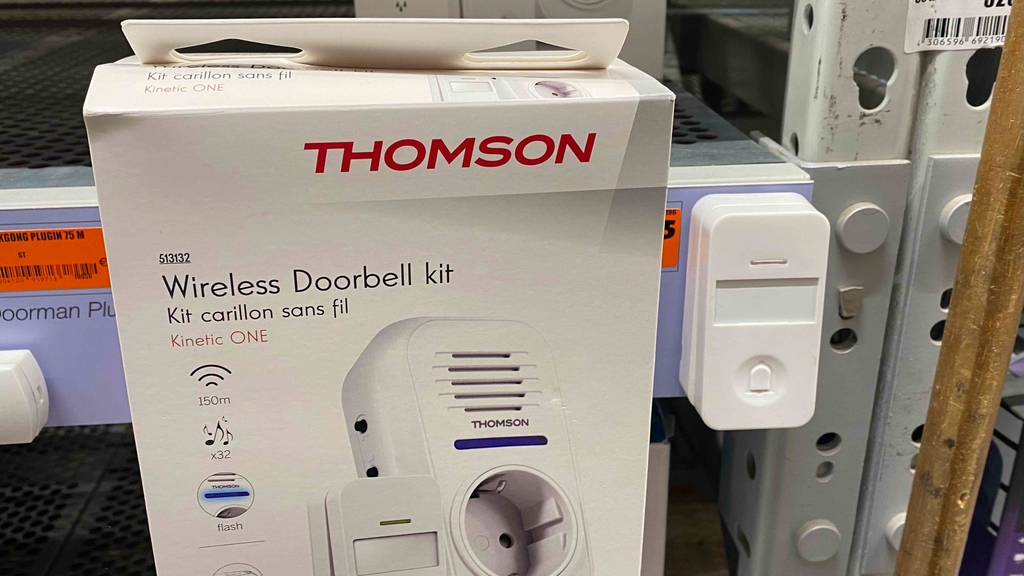 Eine weiße Funkklingel im Test ist an einem Verkaufsregal neben der weißen Verpackung ausgestellt.