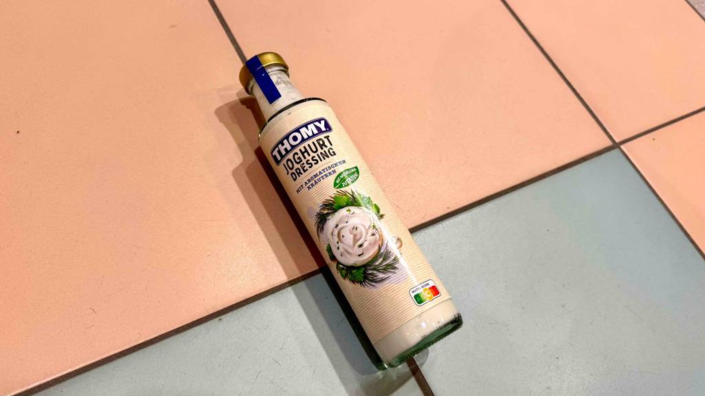 Thomy-Joghurt-Dressing im Test befindet sich in einer Glasflasche auf einem Fliesenbelag.