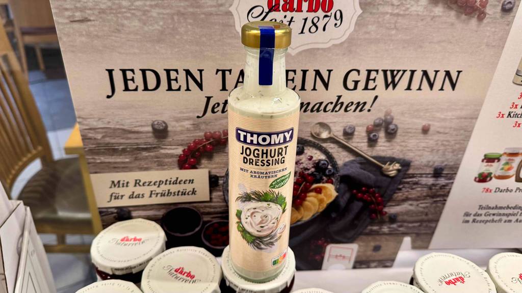 Getestetes Joghurt-Dressing in der Glasflasche steht auf Marmeladengläsern im Geschäft.