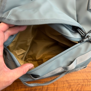 Eine Hand öffnet ein Fach der Thule Chasm Duffel 70L
