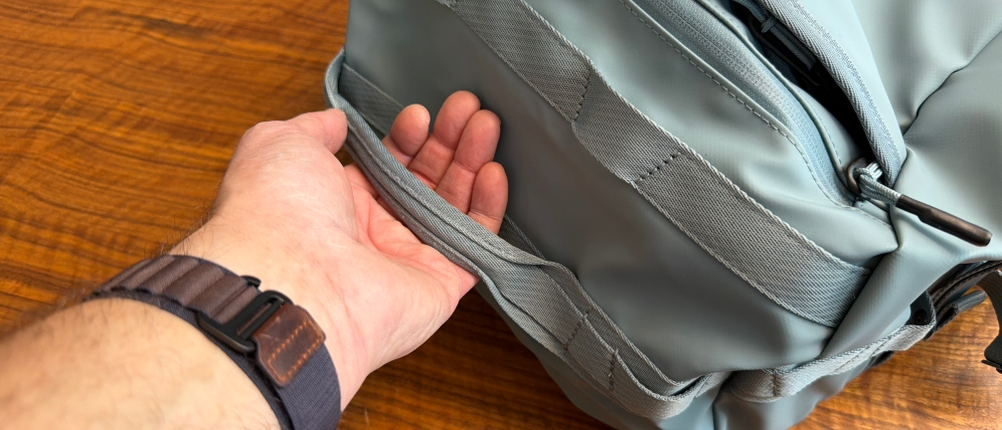 Eine Hand hält den Handgriff der Thule Chasm Duffel 70L fest