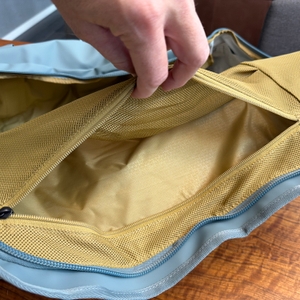 Eine Hand hält ein Netz in der Thule Chasm Duffel 70L auf