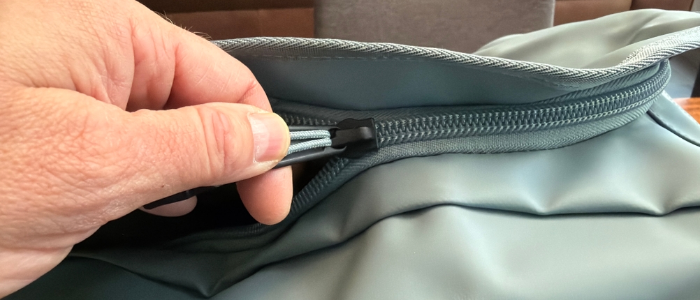 Eine Hand zieht einen Reißverschluss an der Thule Chasm Duffel 70L zu