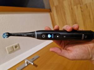 Getestete elektrische Zahnbürste wird in der Hand gehalten.