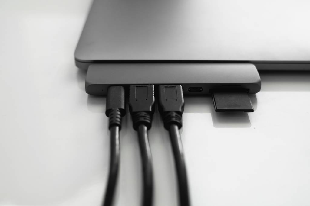 Thunderbolt-3-Dock im Test: Ein Dock, das in direkt ohne Kabel in ein Laptop eingesteckt ist, in dem wiederum drei Kabel und eine SD-Karte stecken.