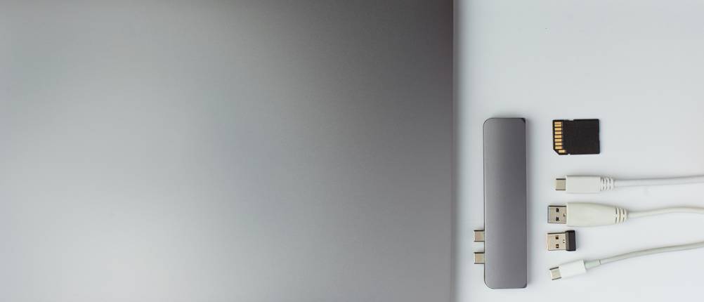 thunderbolt-3-dock-test: Ein Dock liegt nebst Laptop und Steckern auf einem weißen Untergrund.