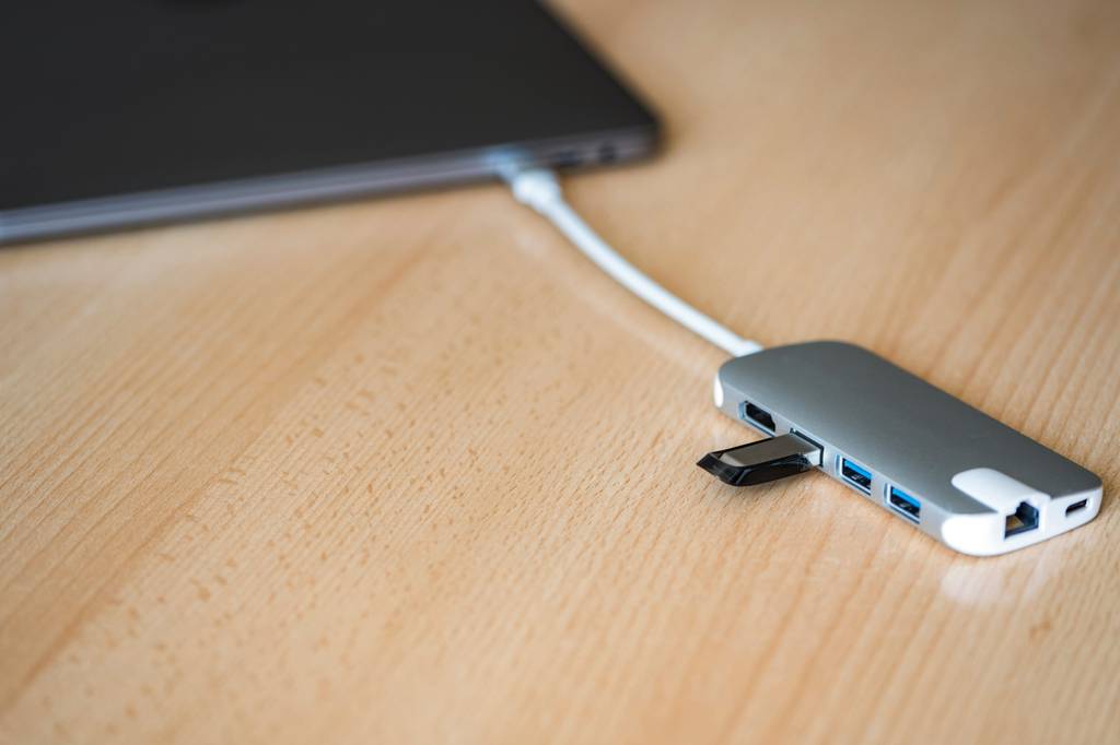 Thunderbolt-3-Dock im Test: Ein Dock mit eingestecktem USB-Stick hängt an einem unscharf sichtbaren Laptop.