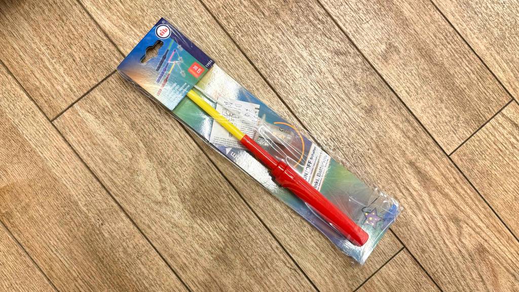 Ein getesteter Laternenstab liegt in Verpackung auf einem Holzboden.