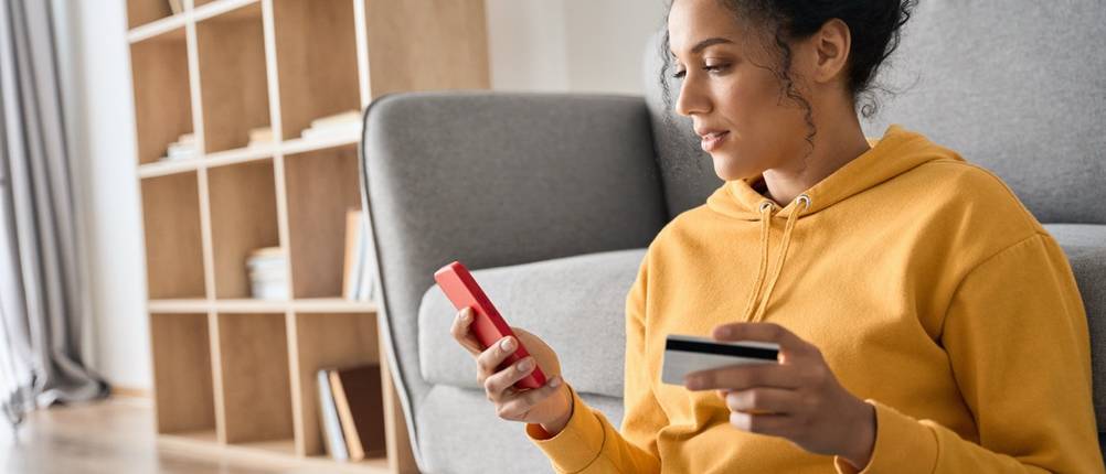 Frau kauft mit Smartphone und Kreditkarte online ein Ticket