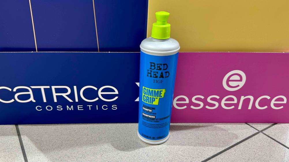 Vor Kartons mit Markenaufdruck steht das getestete Tigi-Shampoo.