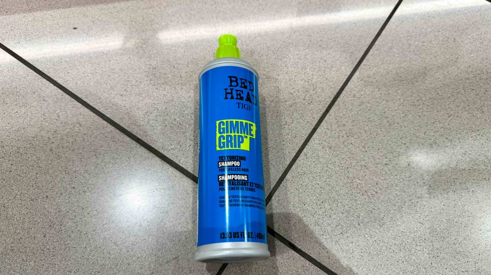 Auf einem Fließenboden liegt eine Flasche Tigi-Shampoo im Test.