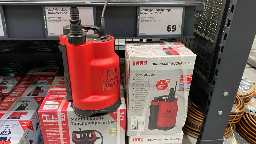 Im Test: Eine Tauchpumpe steht neben ihrer Originalverpackung in einem Verkaufsregal mit Preisangaben.