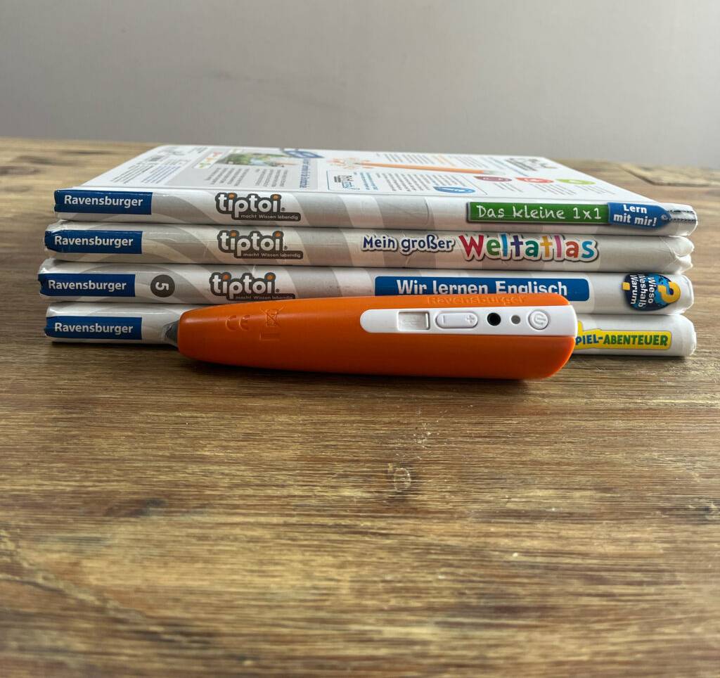 Im Test: Ein Tiptoi-Stift liegt quer vor einem Stapel Tiptoi-Bücher.
