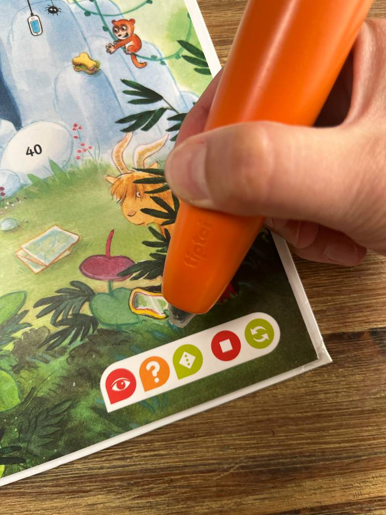 Eine Hand berührt mit einem Tiptoi-Stift im Test eine Stelle im Buch.