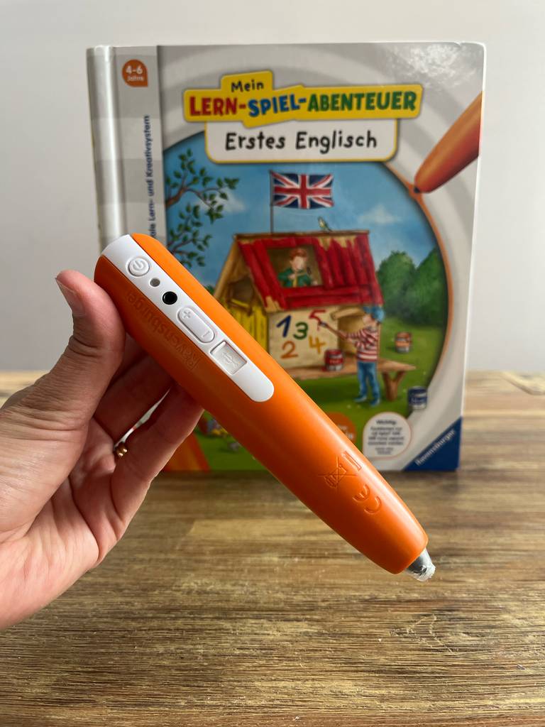 Im Test: Eine Hand hält einen Tiptoi-Stift vor ein Englisch-Tiptoi-Buch.