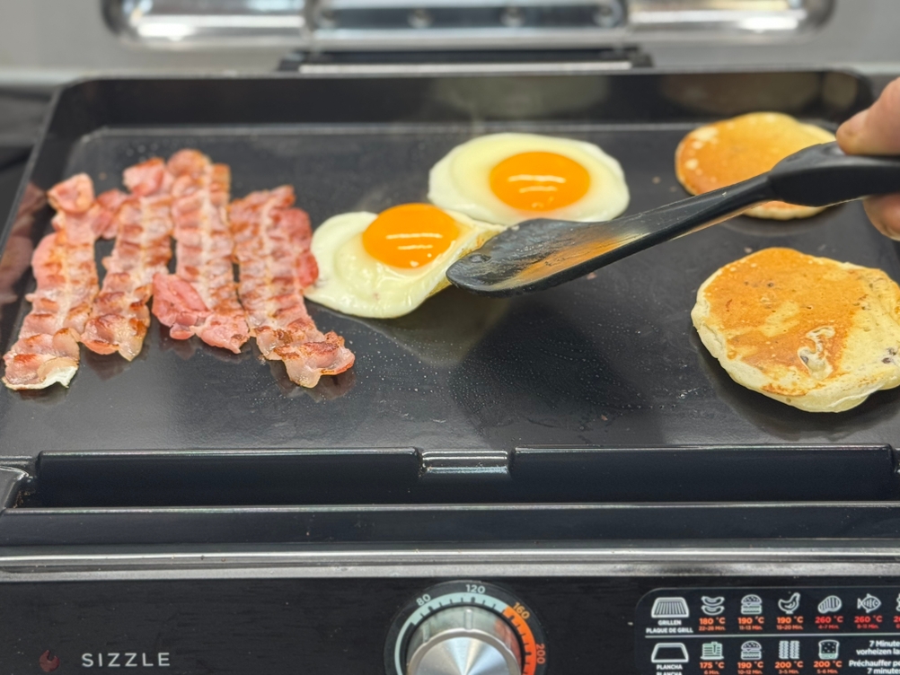 Eine Person wendet auf dem getesteten Tischgrill von Ninja ein Spiegelei.