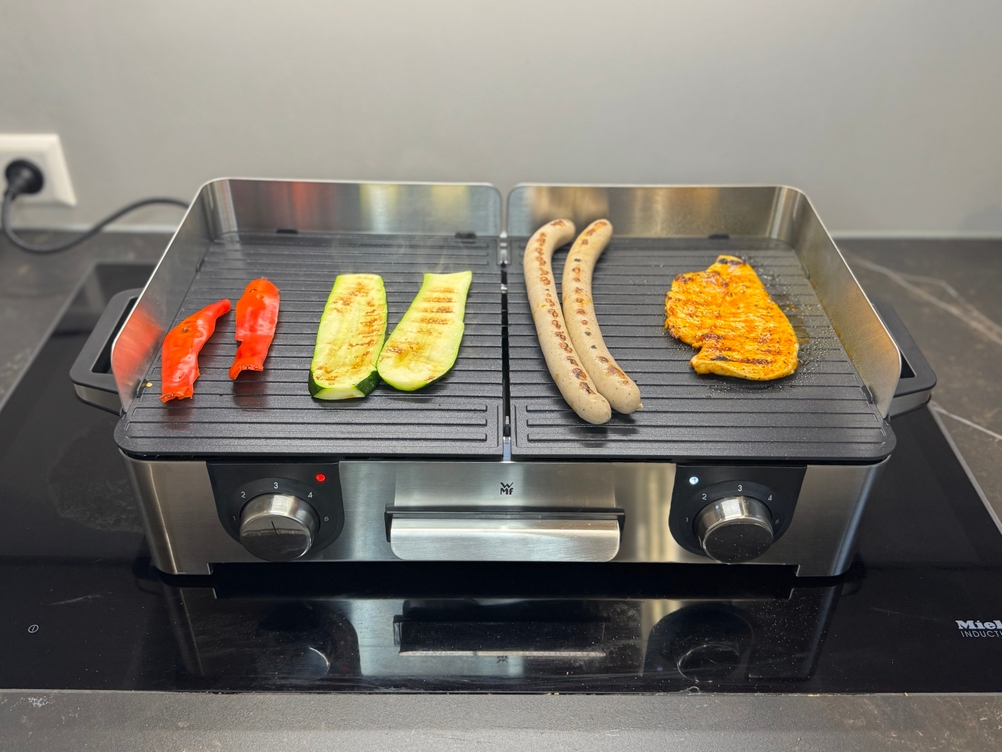 Auf dem getesteten Tischgrill von WMF werden Paprika, Zucchini, Bratwürste und Hähnchen gegrillt.
