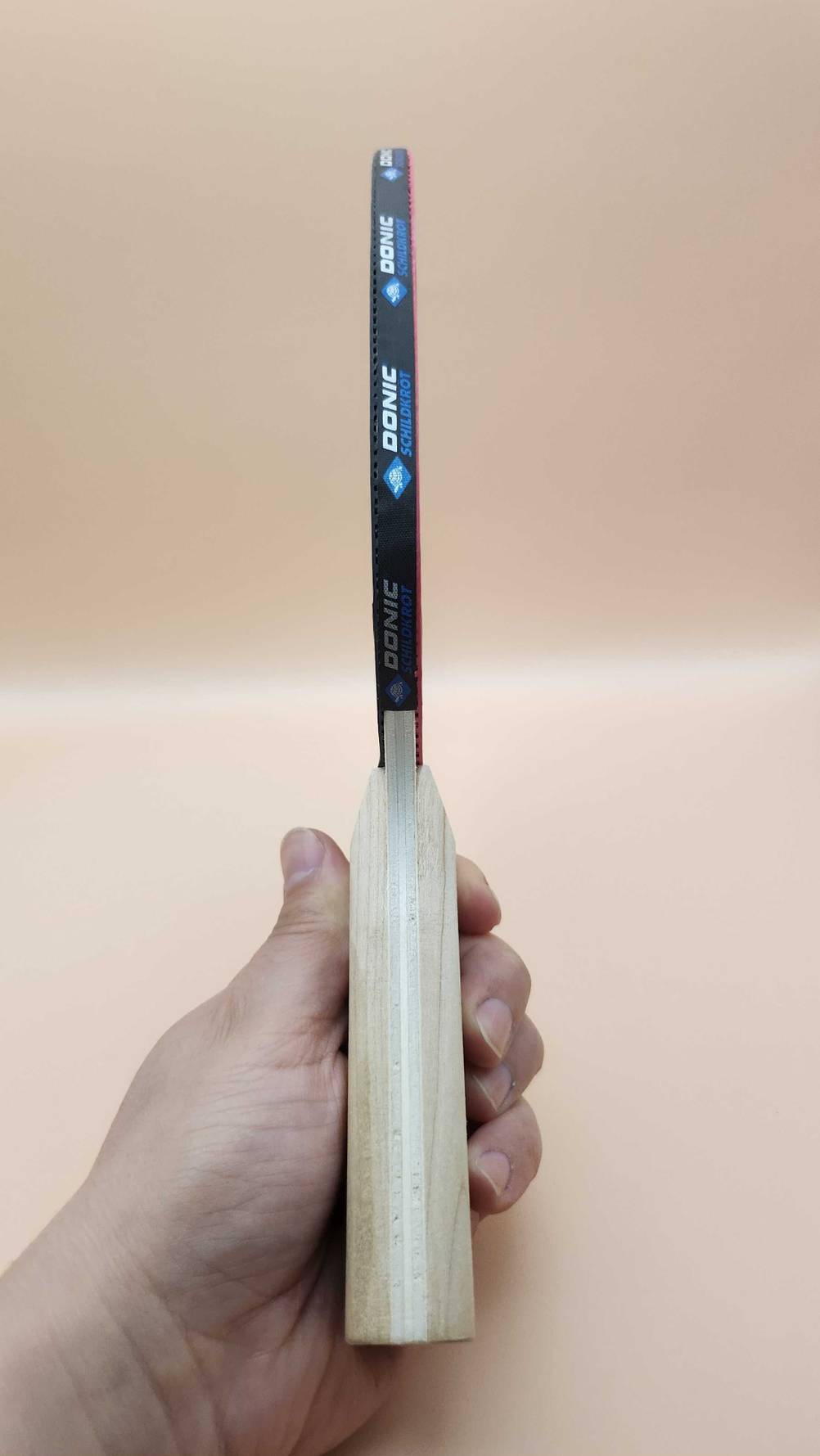 Seitenansicht eines getesteten Tischtennis-Holz von einer Hand gehalten.