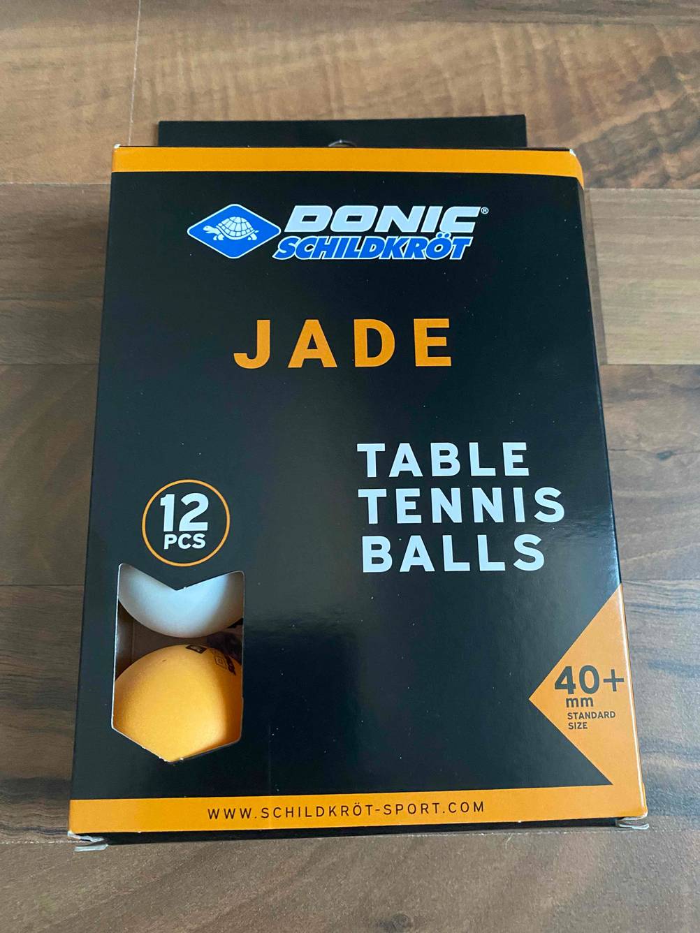 Mehrere getestete Tischtennisbälle befinden sich verpackt auf einem Holztisch. 