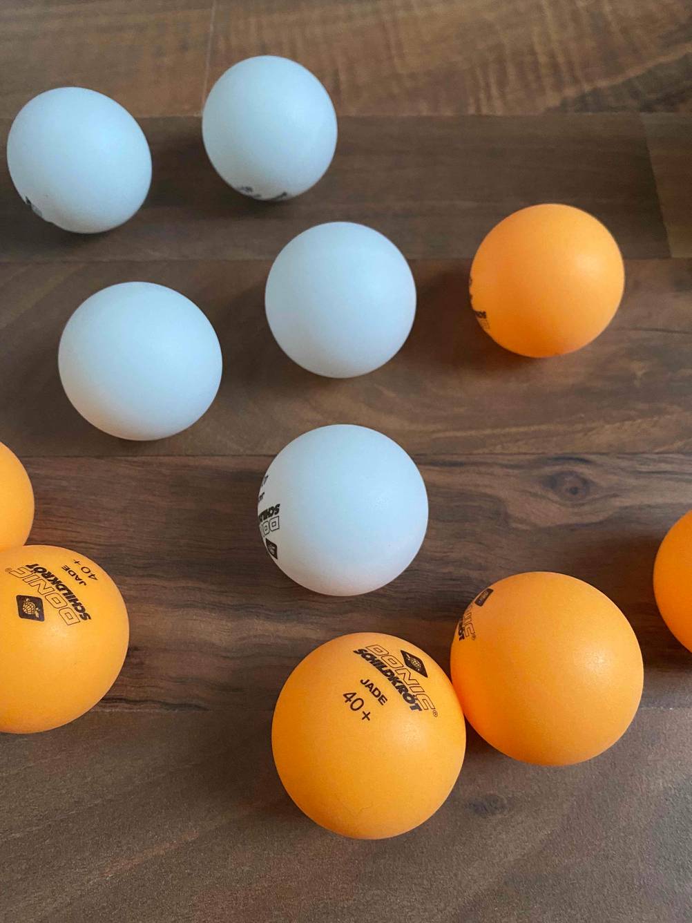 Tischtennisbälle im Test: Verschiedenfarbige Tischtennisbälle befinden sich auf einem Holztisch. 