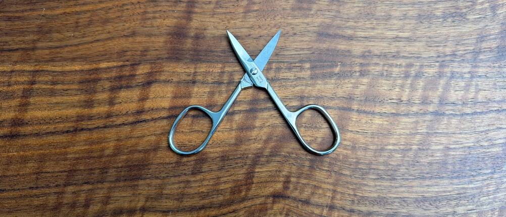 Die Titania-Nagelschere liegt geöffnet auf einem Holztisch.