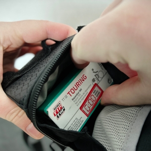 Ein kleines Reparaturset wird in eine Tasche gelegt. Der TKMARS GPS Tracker ist darunter versteckt.