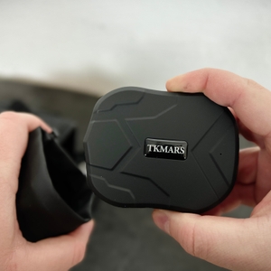 Das TKMARS GPS Gerät wird mit der Hand in eine schwarze Schutzhülle geschoben. Das Gehäuse ist strukturiert und mit einem Logo versehen.