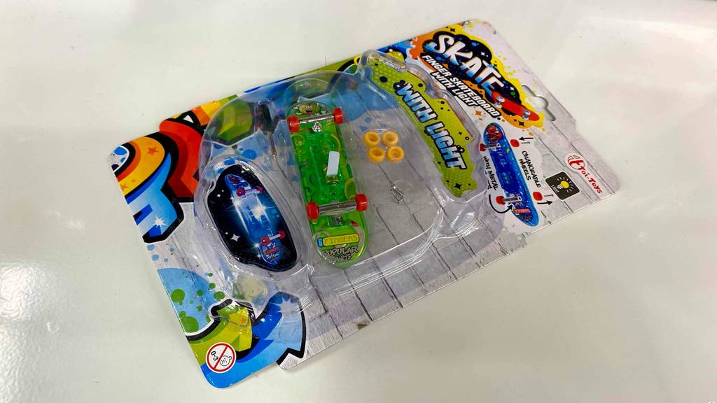 Getestet: Finger-Skateboard ist in einer durchsichtigen Originalverpackung eingeschweißt und liegt auf einem hellen Untergrund.