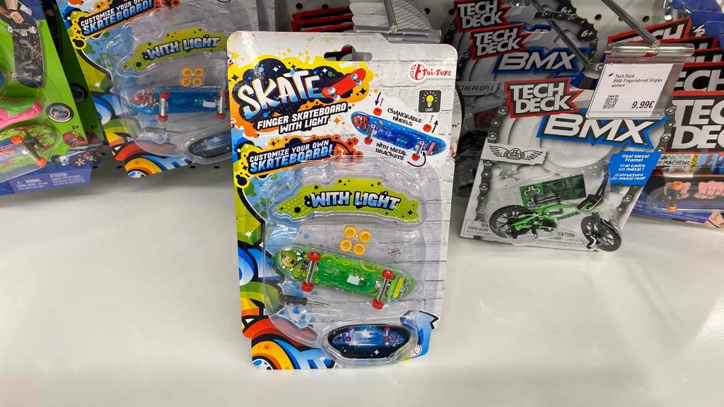 Finger-Skateboard-Test: Finger-Skateboard in einer durchsichtigen Originalverpackung steht vor einem Verkaufsregal mit weiteren Spielzeugen.