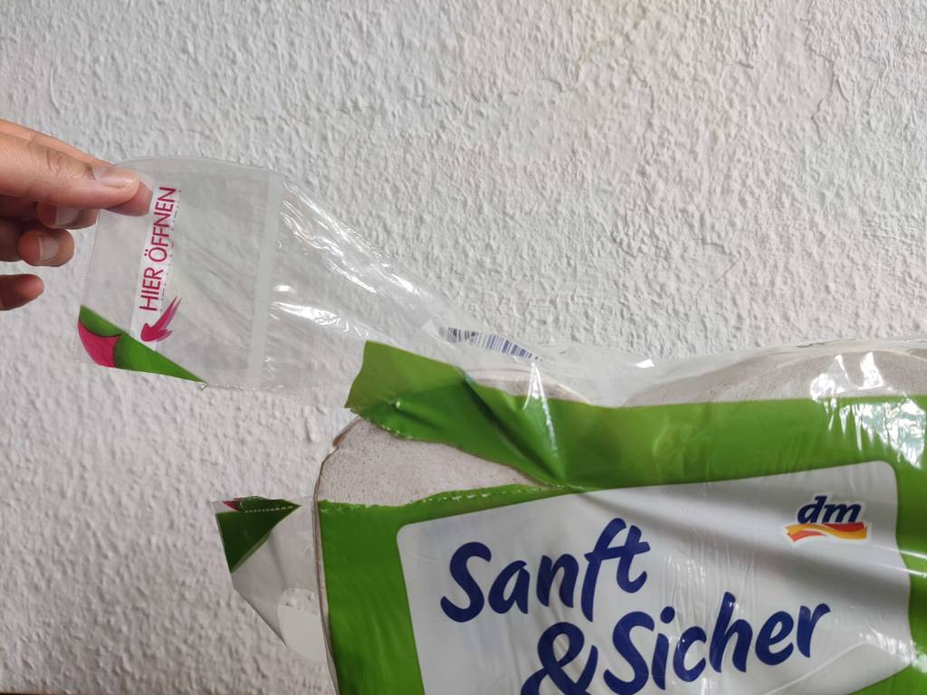 Ein 3-lagiges Toilettenpapier im Test: Hand öffnet eine Toilettenpapier-Packung. 