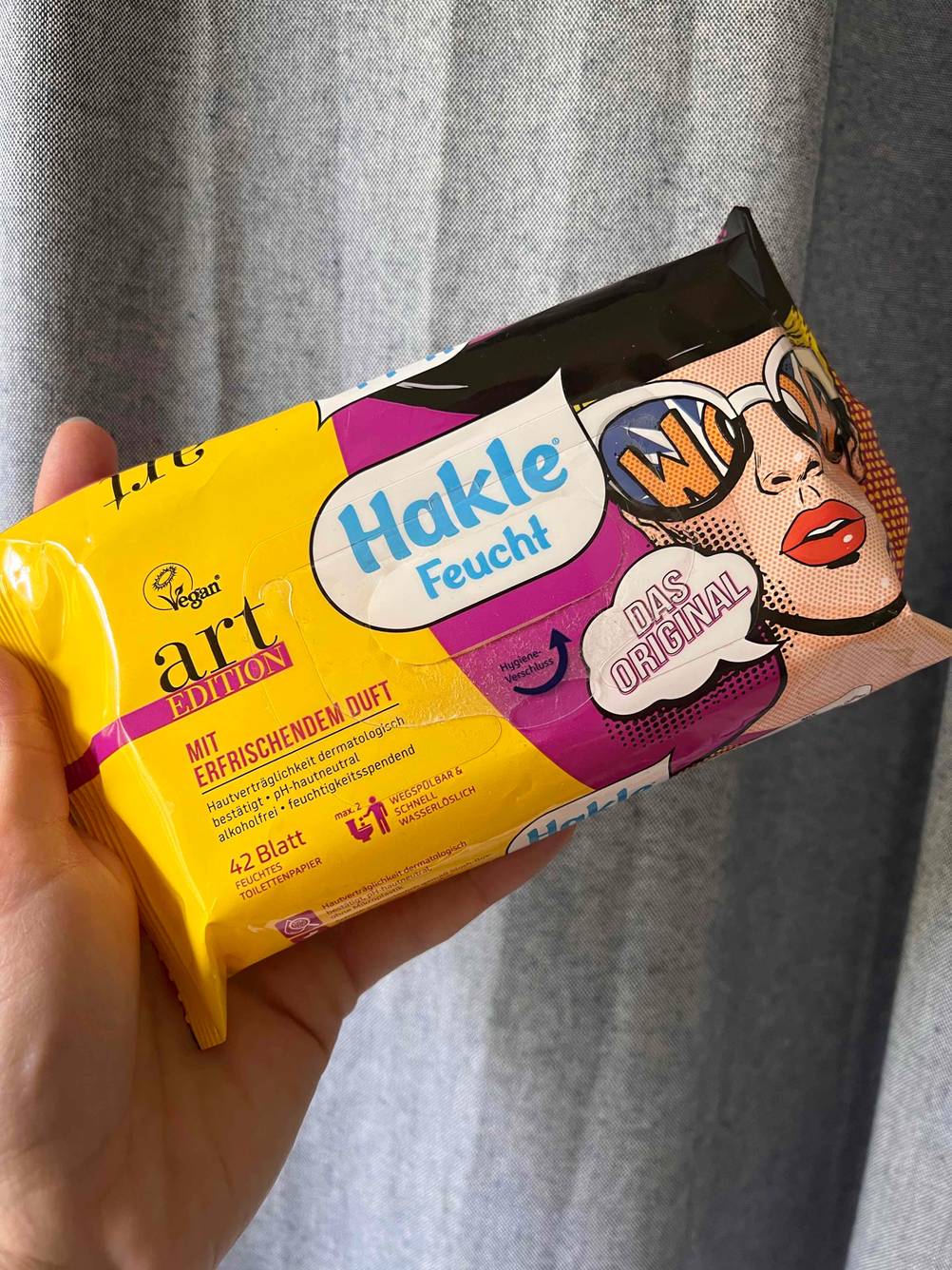 Eine Hand hält eine getestete Toilettenpapier-Packung. 