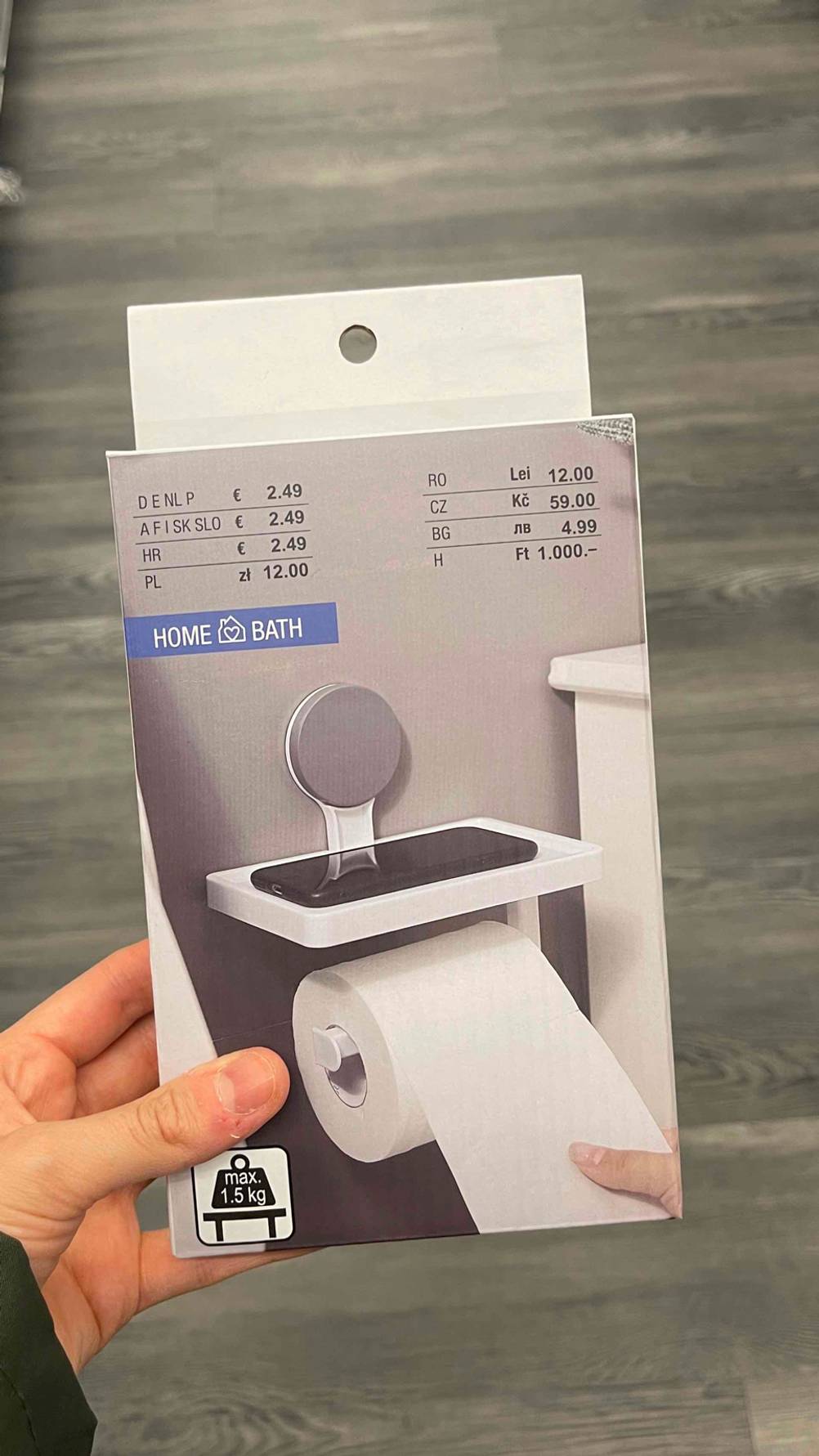 Der verpackte Toilettenpapierhalter im Test von einer Hand gehalten.