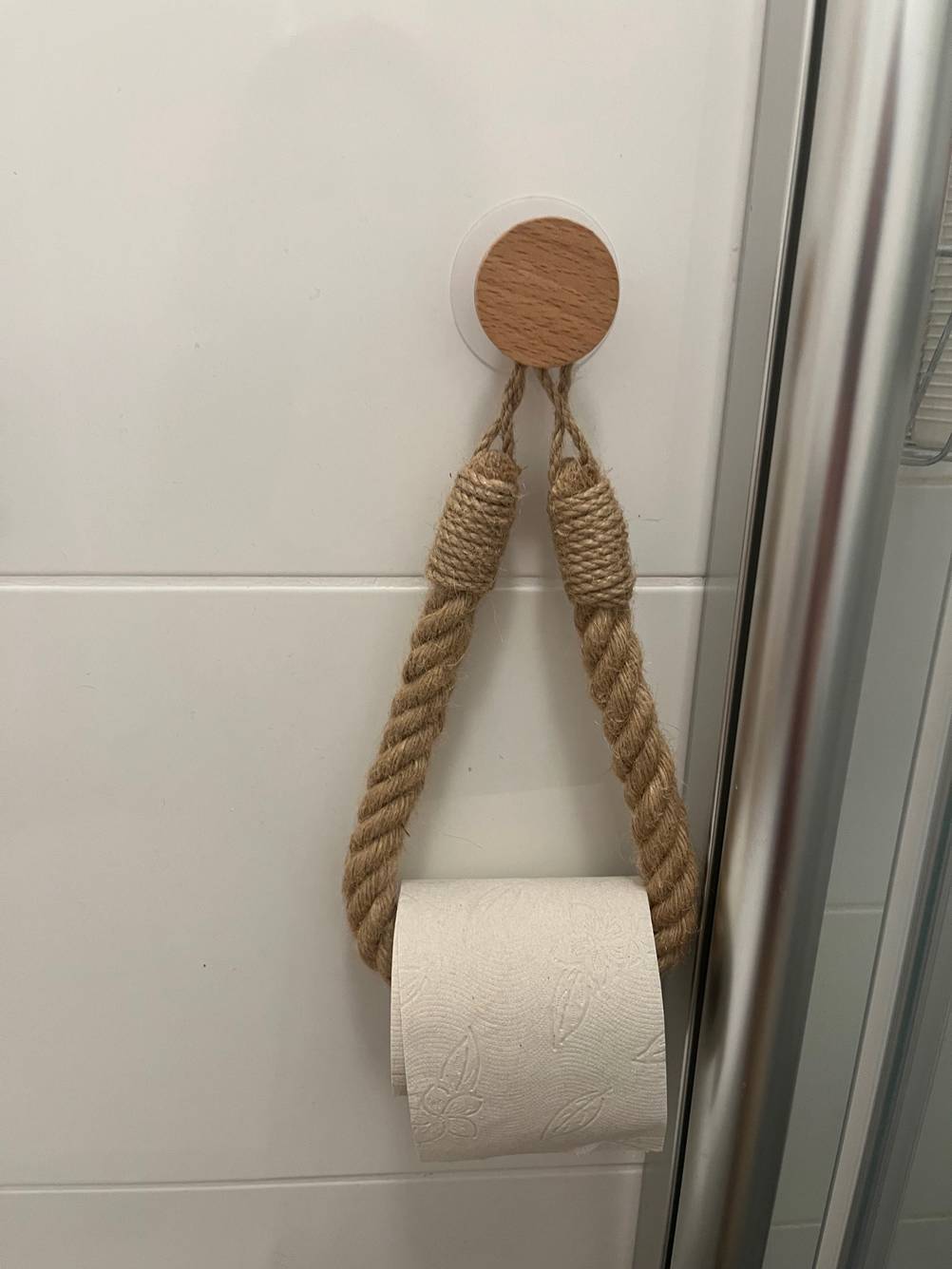 Ein Toilettenpapierhalter ohne Bohren im Test mit Klorolle an einer weißen Fließenwand.
