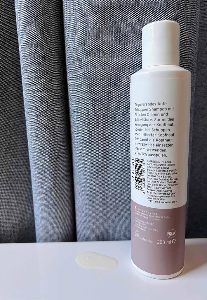 Antischuppenshampoo getestet: Eine Flasche mit der Rückseite nach vorne vor einem grauen Vorhang.