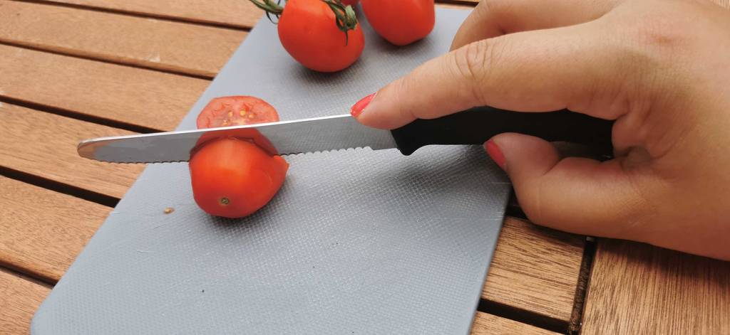 tomatenmessser-test: Aufschneiden einer Tomate mit einem Tomatenmesser auf einem Küchenbrett