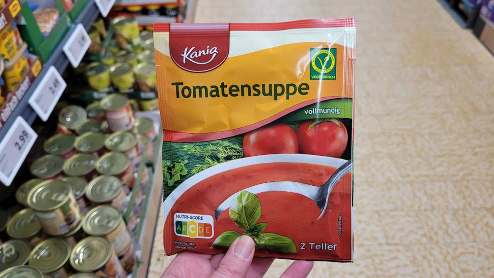 Eine Hand hält eine Packung der getesteten Tomatensuppe hoch.