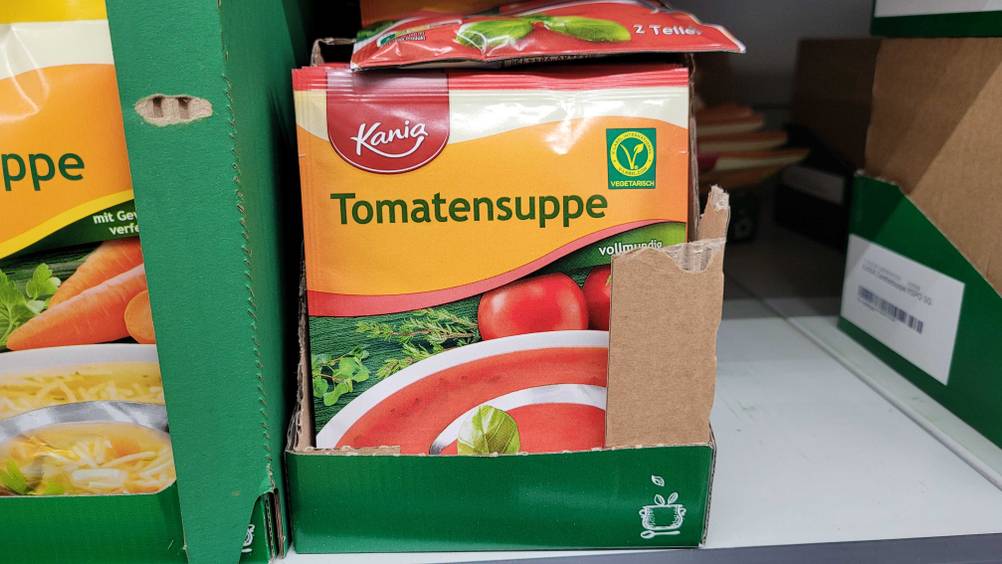 Mehrere Packungen der getesteten Tomatensuppe in einem Karton auf einem Regal.