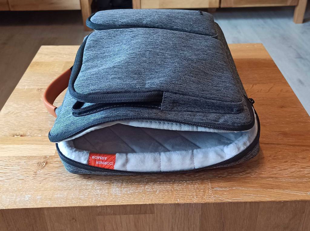 Blau melierte getestete MacBook-Tasche befindet sich mit geöffnetem Reißverschluss auf einer Holzfläche.