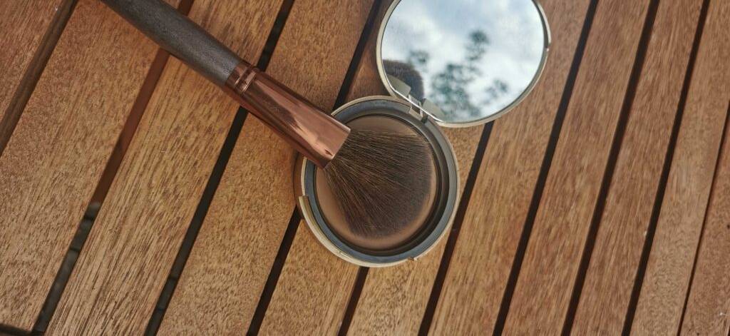Bronzer Test: Ein Schminkpinsel liegt auf dem Bronzer einer Schminkdose inklusive Spiegel im Deckel.